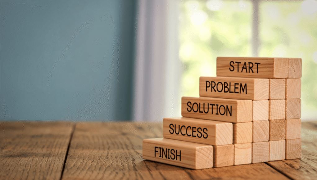 Stack of wooden blocks labeled START, PROBLEM, SOLUTION, SUCCESS, FINISH, symbolizing a problem-solving process.