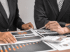 IRS Cryptocurrency Tax Rules 2026: What Investors Must Report Two professionals in suits review financial charts and graphs spread across a desk, using a pen and calculator nearby.