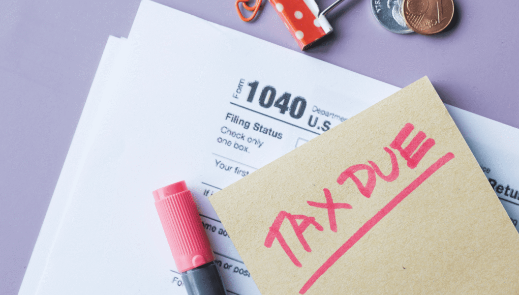 Tax form 1040 with a pink 'TAX DUE' stamp on a beige note and a pink marker on a lavender background