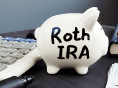 Roth Conversion Strategy 2026: How High-Income Earners Can Save on Taxes White piggy bank labeled Roth IRA on a desk next to a calculator, pen, wallet, and stacks of cash—conveys retirement savings.